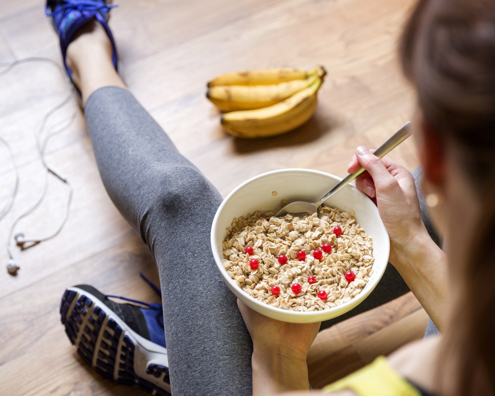 Woman in fitness attire eating oatmeal with berries