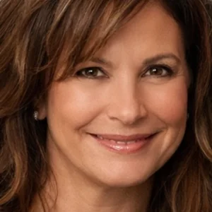 Close-up headshot of a smiling woman with brown hair and subtle makeup, looking at the camera.